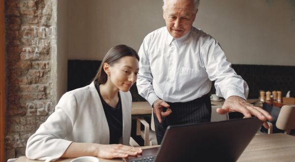 Two business partners working with a laptop in a cafe