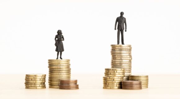 Gender Wage gap concept Man and woman figurines standing on top of the pile of coins