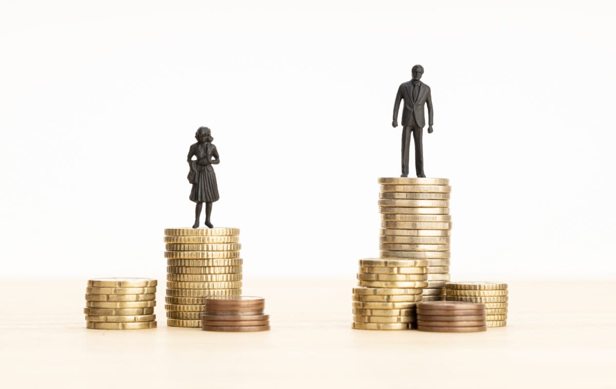 Gender Wage gap concept Man and woman figurines standing on top of the pile of coins
