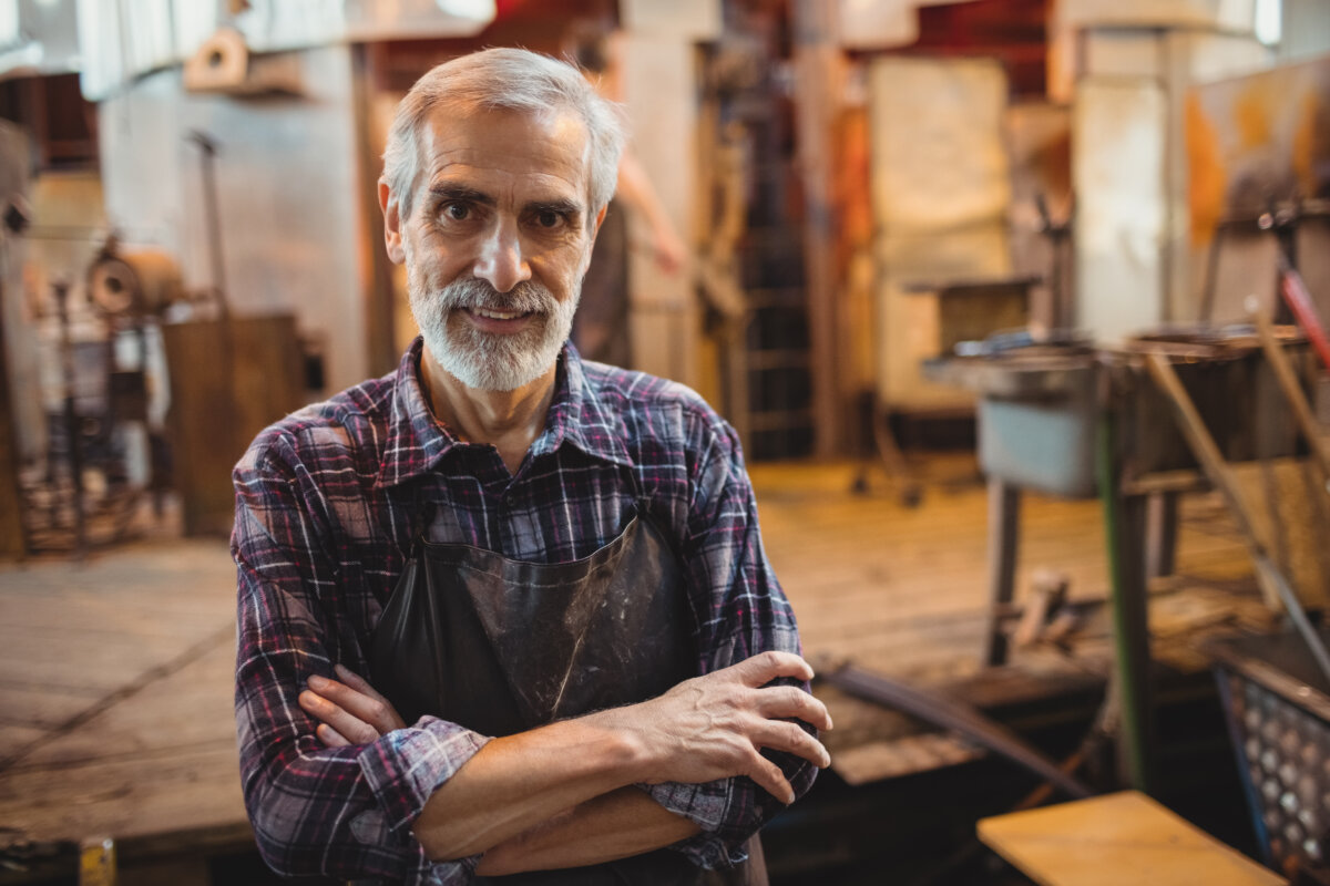 Portrait of glassblower standing with arms crossed at glassblowing factory