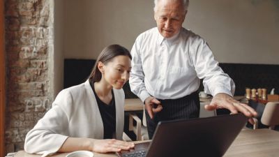 Two business partners working with a laptop in a cafe
