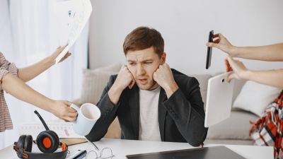 Many hands reach out to a man with various objects